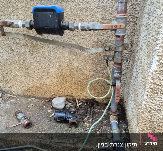 צינורות מים עם מחברים וברזים על קיר חיצוני